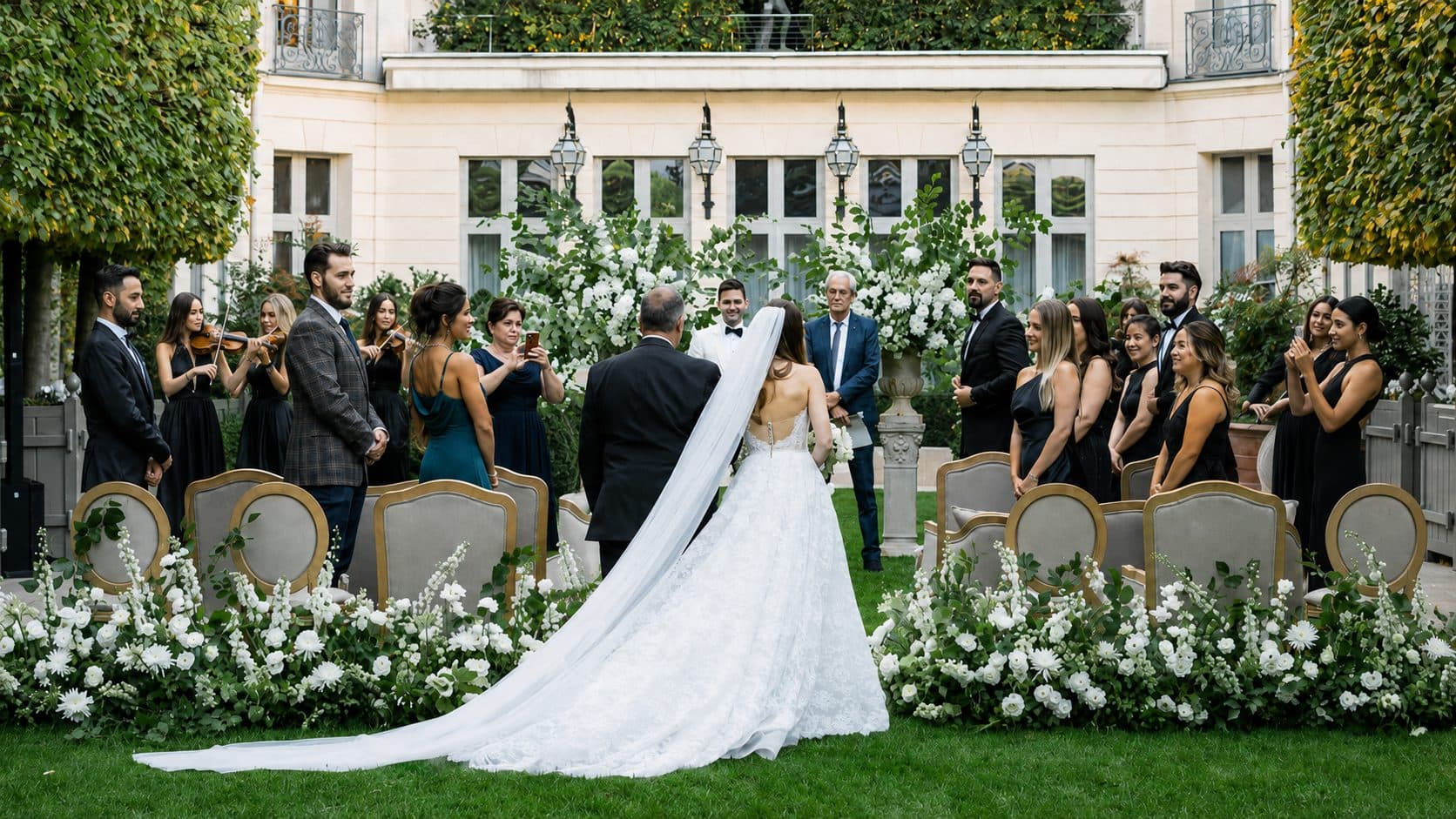 Cérémonie de mariage en extérieur devant un hôtel particulier, la mariée remonte l’allée fleurie entre les invités assis