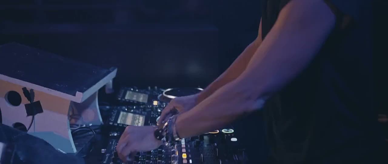 Mains d’un DJ sur sa console lumineuse, gros plan dans une lumière bleue et violette